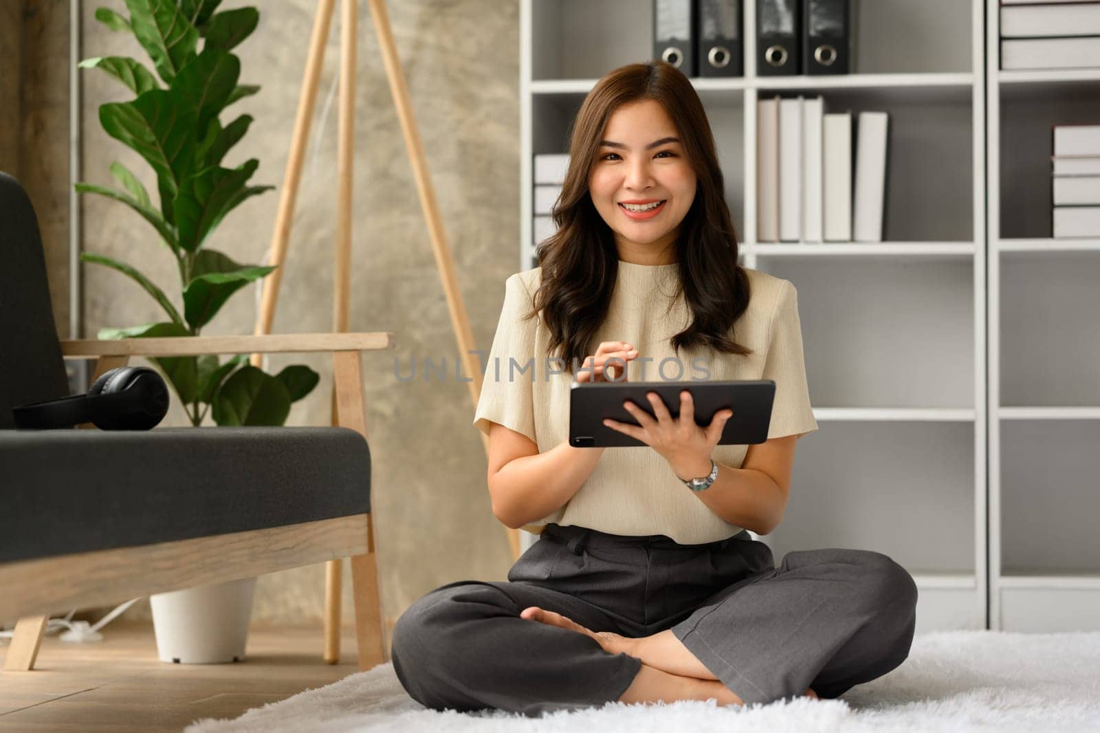 Full length of happy millennial woman using digital tablet in living room. Technology, people and lifestyle concept.