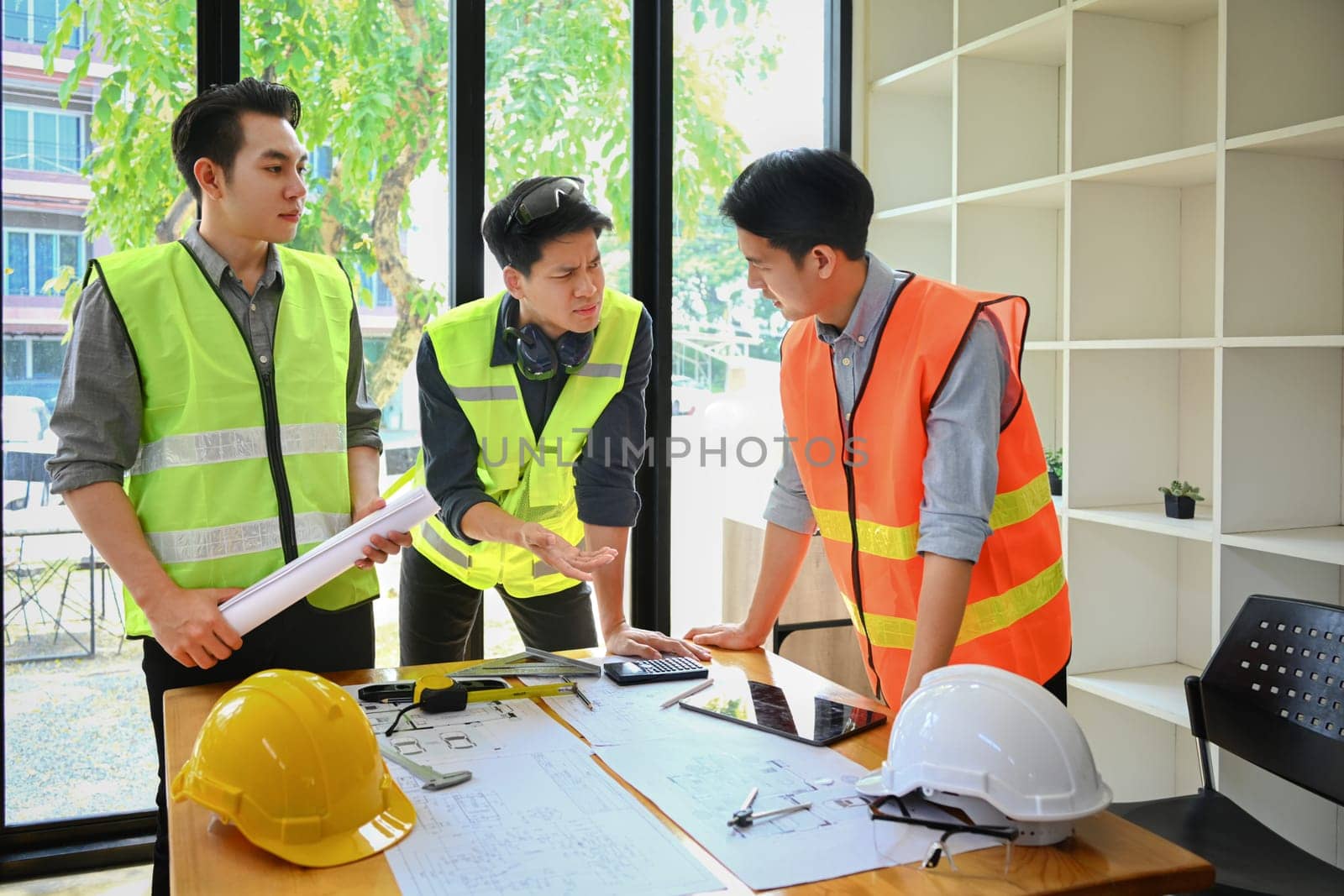 Architect team brainstorming, planning development details at construction office.