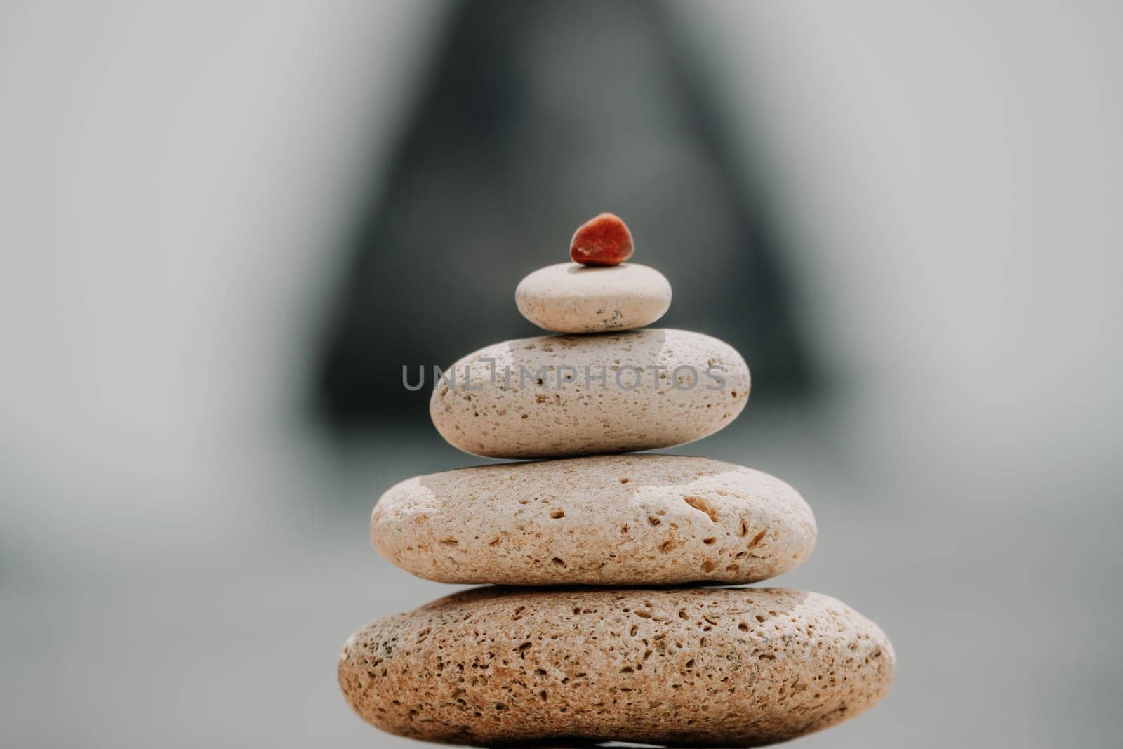 Pyramid stones on the seashore with warm sunset on the sea background. Happy holidays. Pebble beach, calm sea, travel destination. Concept of happy vacation on the sea, meditation, spa, calmness.