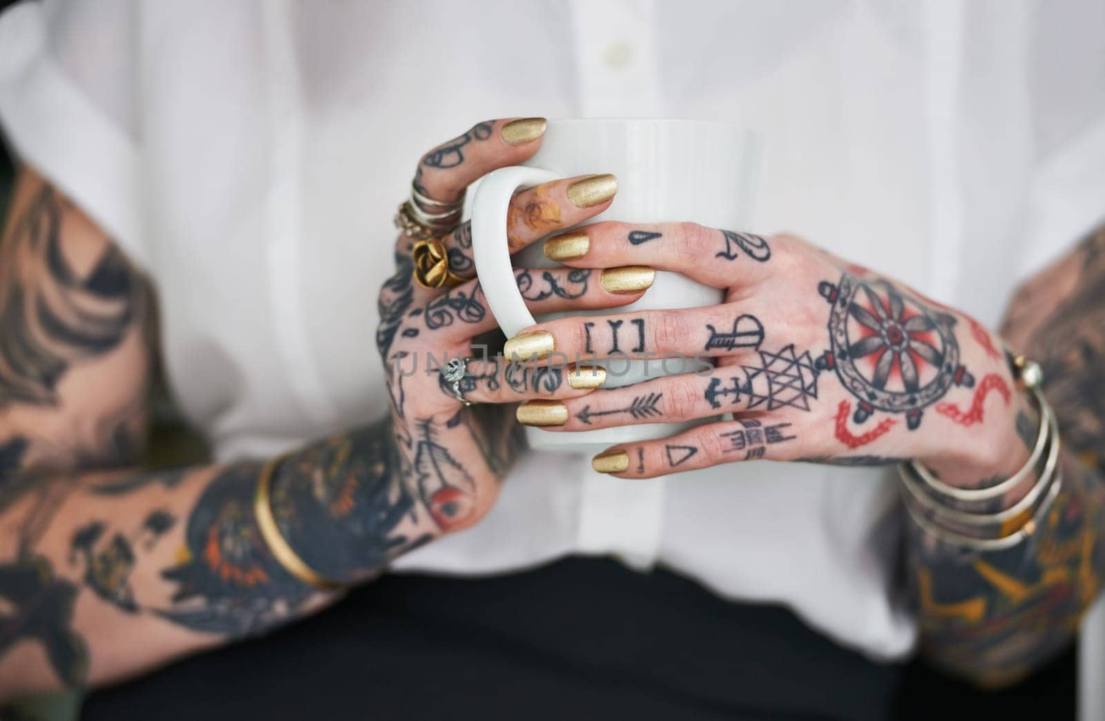 She loves her tattoos. Shot of an unrecognizable tattooed businesswoman holding a mug. by YuriArcurs