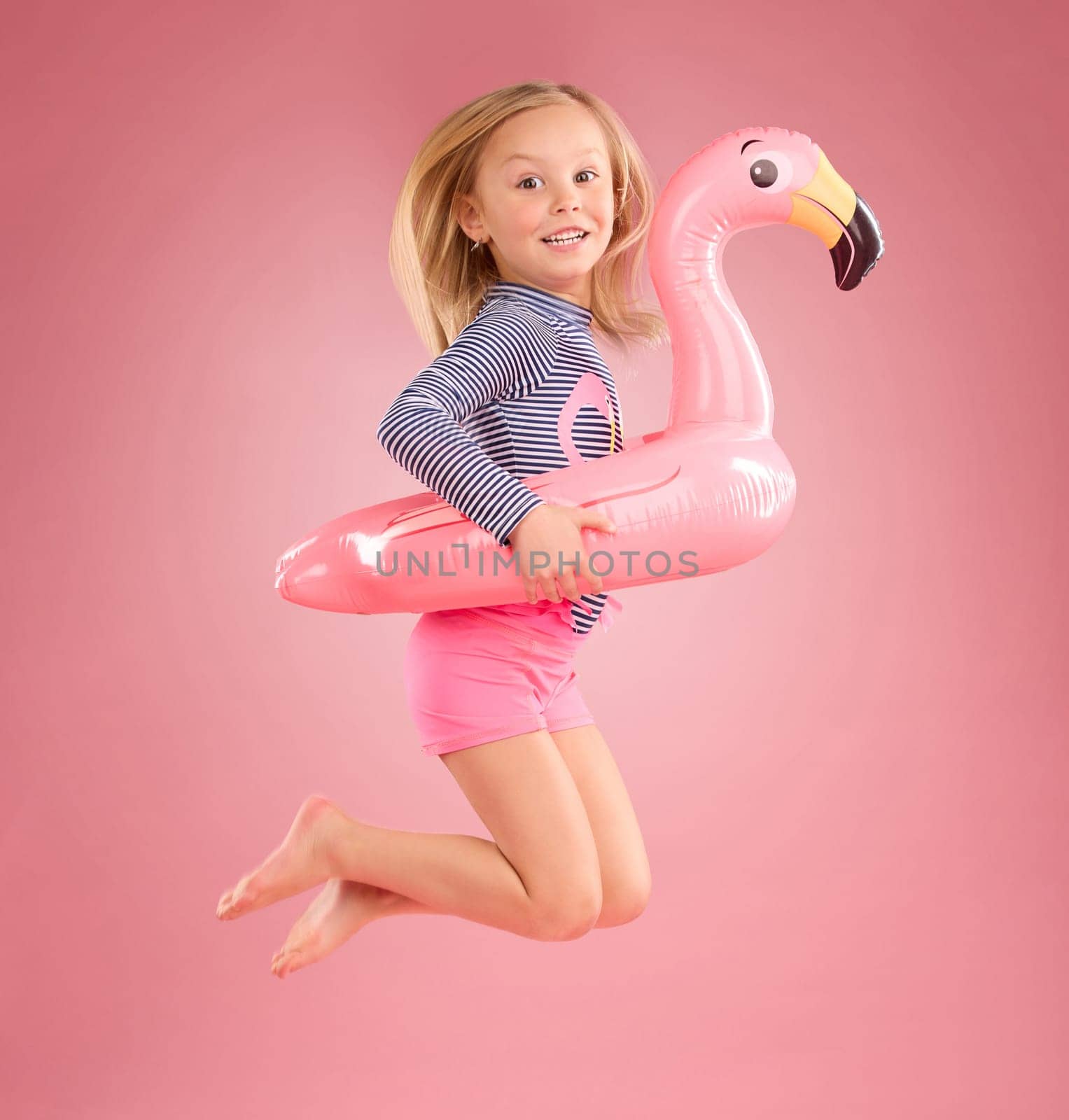 Jump, smile and portrait of girl and pool float for swimming, summer break or happiness. Youth, funny and inflatable with child and flamingo ring for cute, happy or beach holiday on pink background.