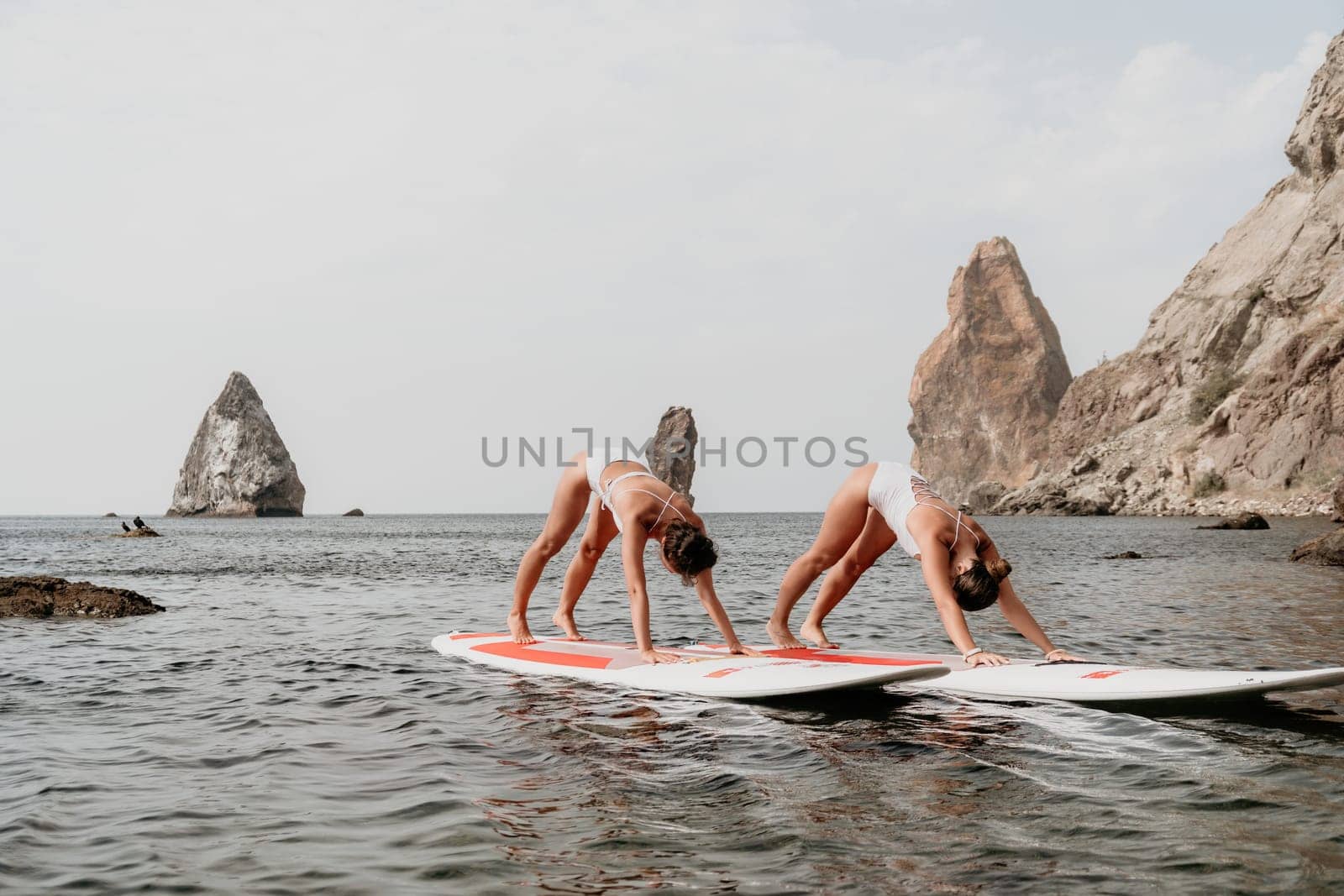 Woman sup yoga. Middle age sporty woman practising yoga pilates on paddle sup surfboard. Female stretching doing workout on sea water. Modern individual hipster outdoor summer sport activity