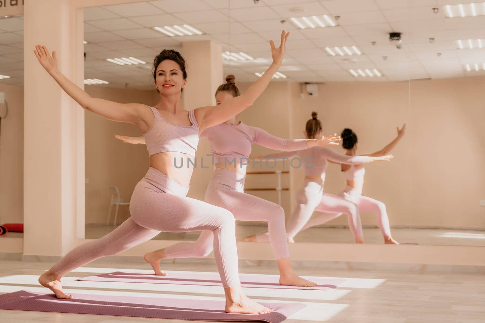 Young woman with long hair in white swimsuit and boho style braclets practicing outdoors on yoga mat by the sea on a sunset. Women's yoga fitness routine. Healthy lifestyle, harmony and meditation