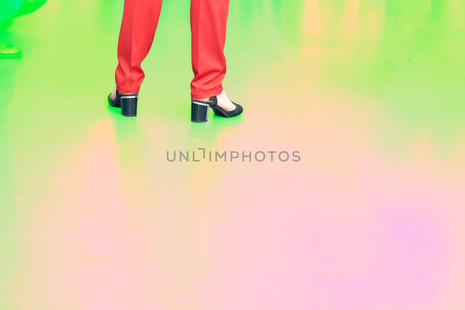 Woman legs in red trousers and black sandals shoes on a yellow pink green by jovani68