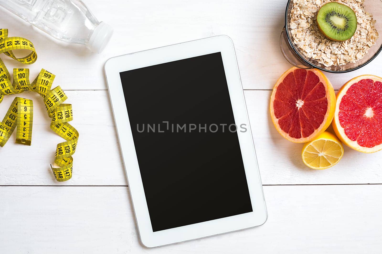 Fresh fruits with tape measure over white wooden background. Fitness concept. Top view. Copy space Flat lay