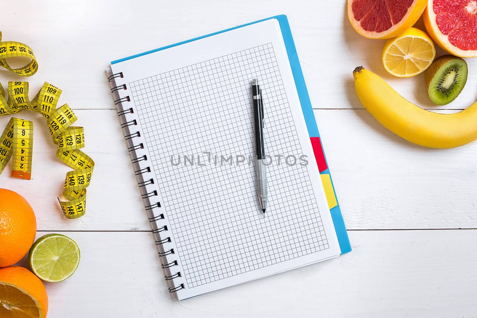 Fresh fruits with tape measure over white wooden background. Fitness concept. Top view. Copy space Flat lay