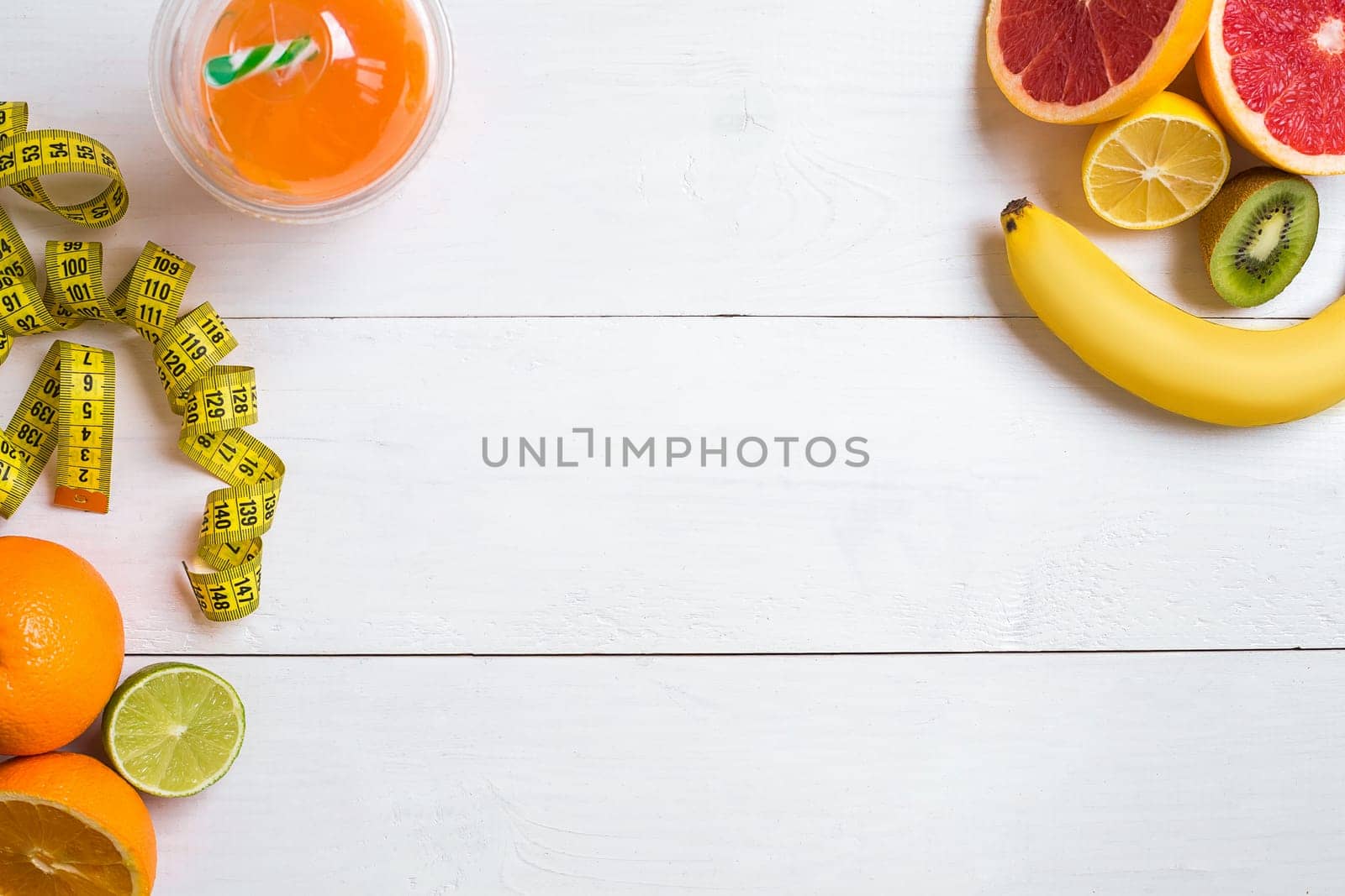 Fresh fruits with tape measure over white wooden background. Fitness concept. Top view. Copy space Flat lay