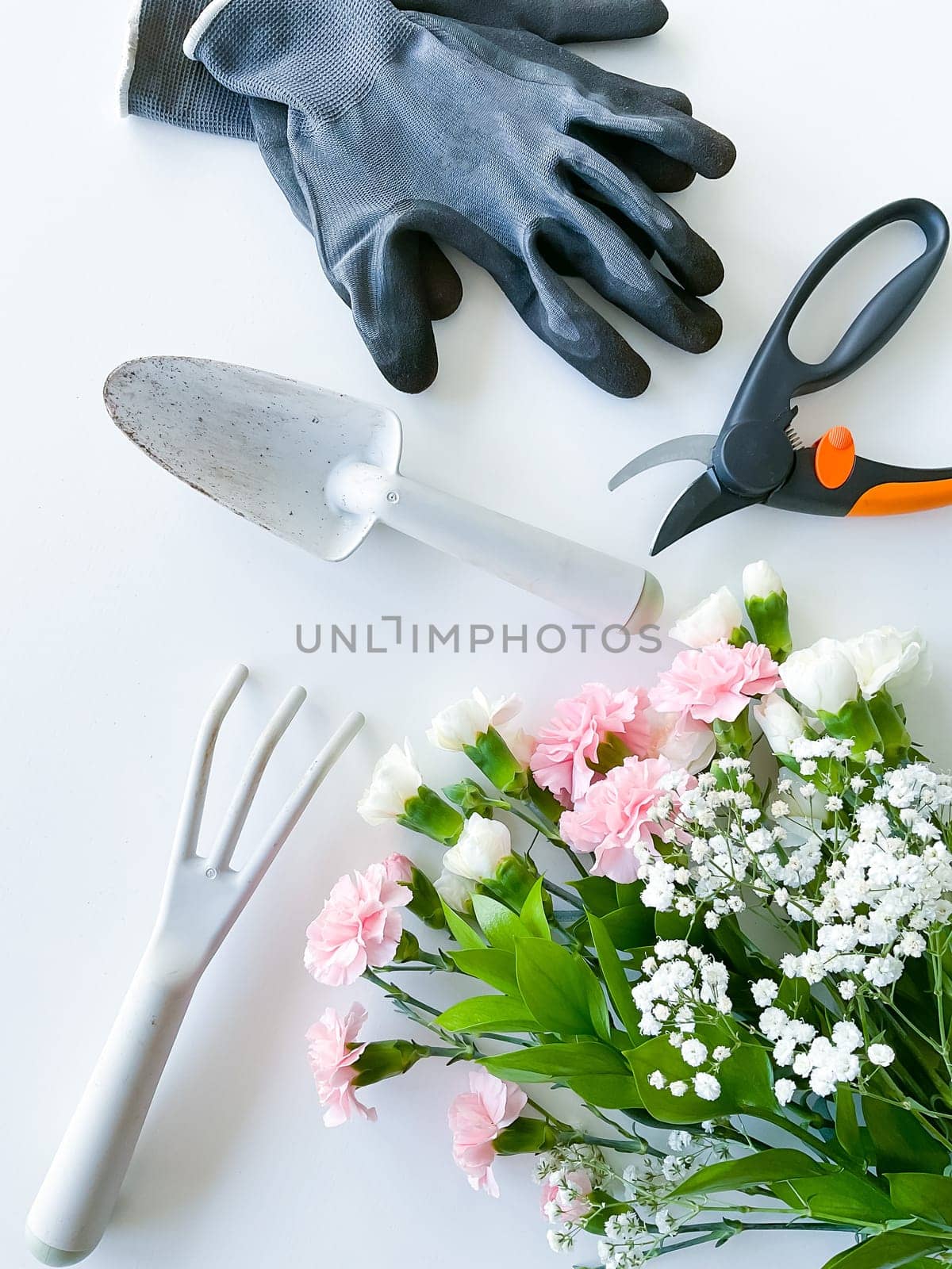 spray pink and white flowers with gardening tools on white background