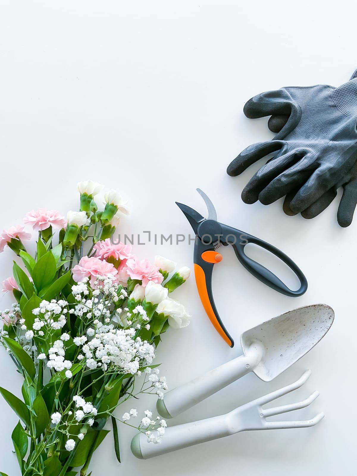spray pink and white flowers with gardening tools on white background