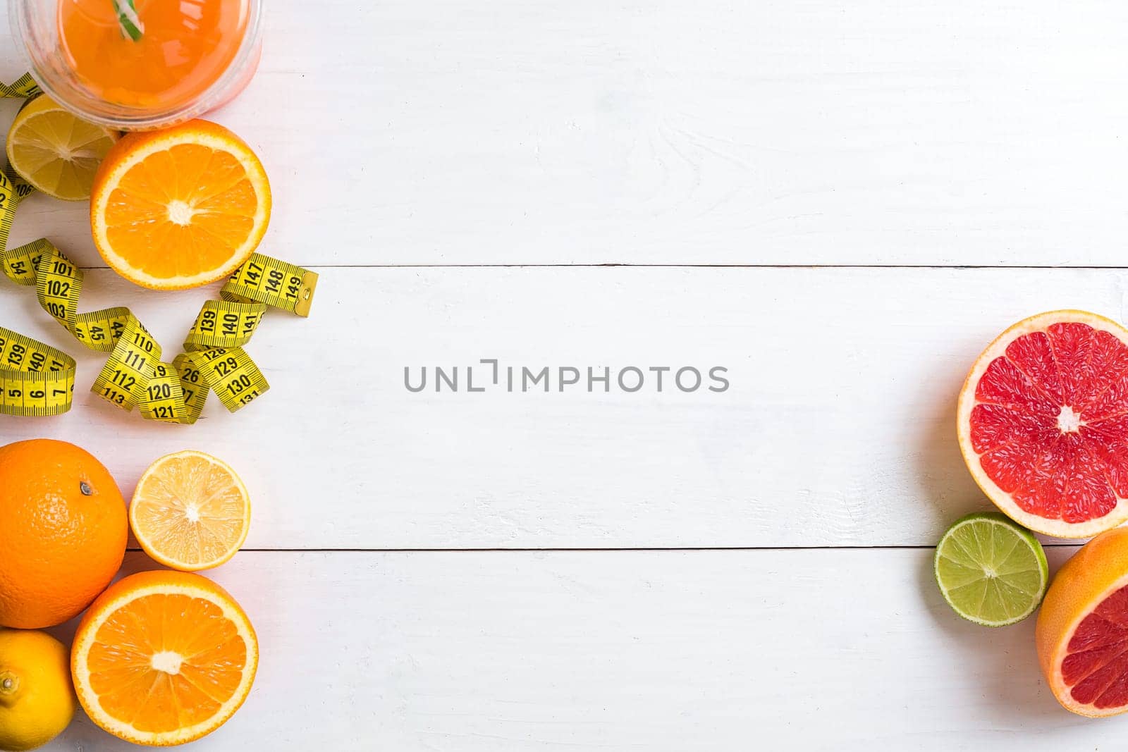 Fresh fruits with tape measure over white wooden background. Fitness concept. Top view. Copy space Flat lay