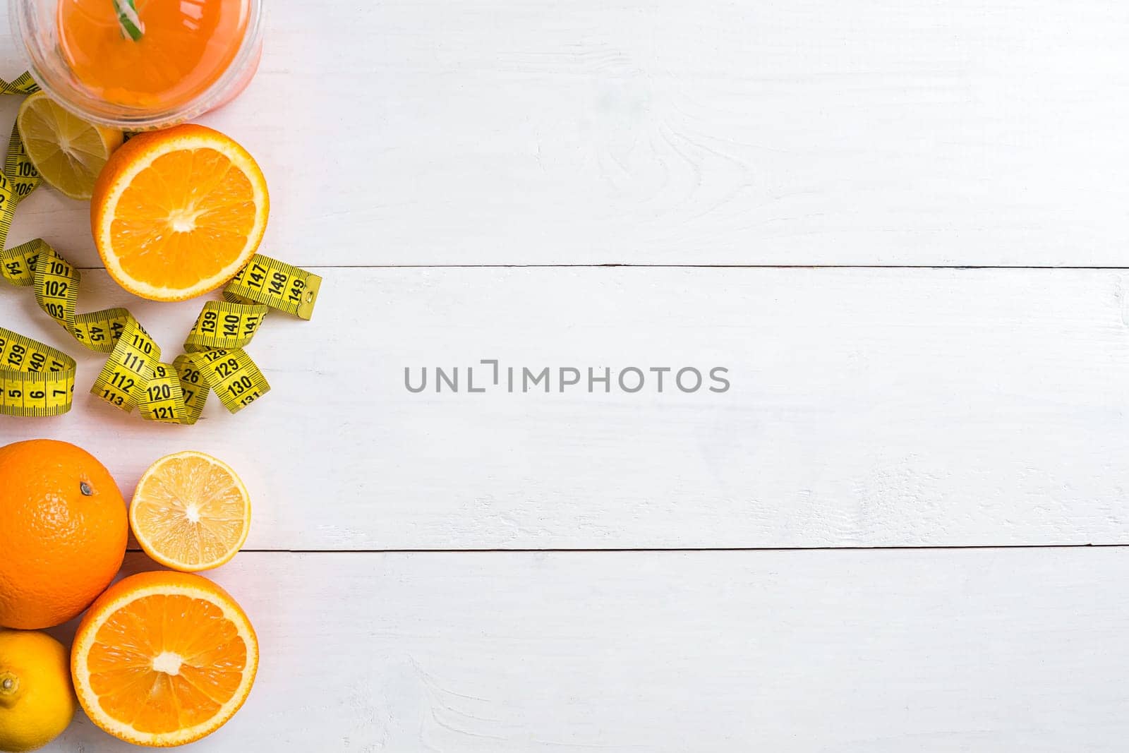 Fresh fruits with tape measure over white wooden background. Fitness concept. Top view. Copy space Flat lay