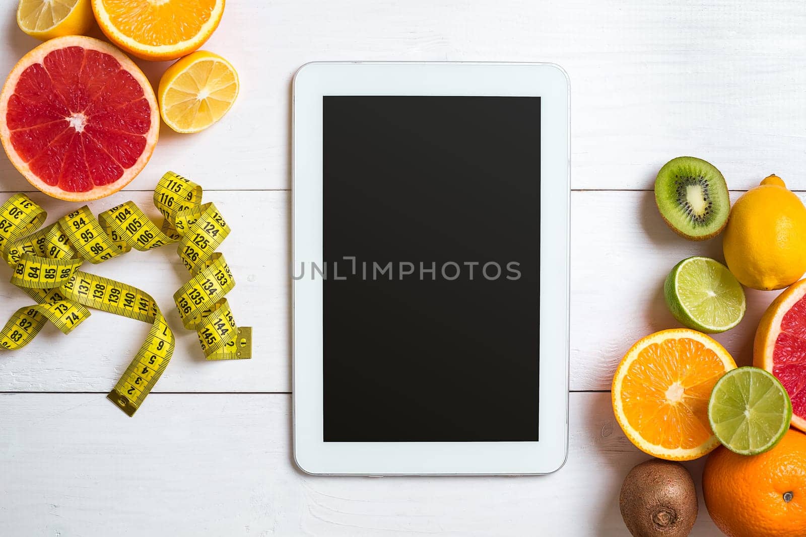 Fresh fruits with tape measure over white wooden background. Fitness concept. Top view. Copy space Flat lay