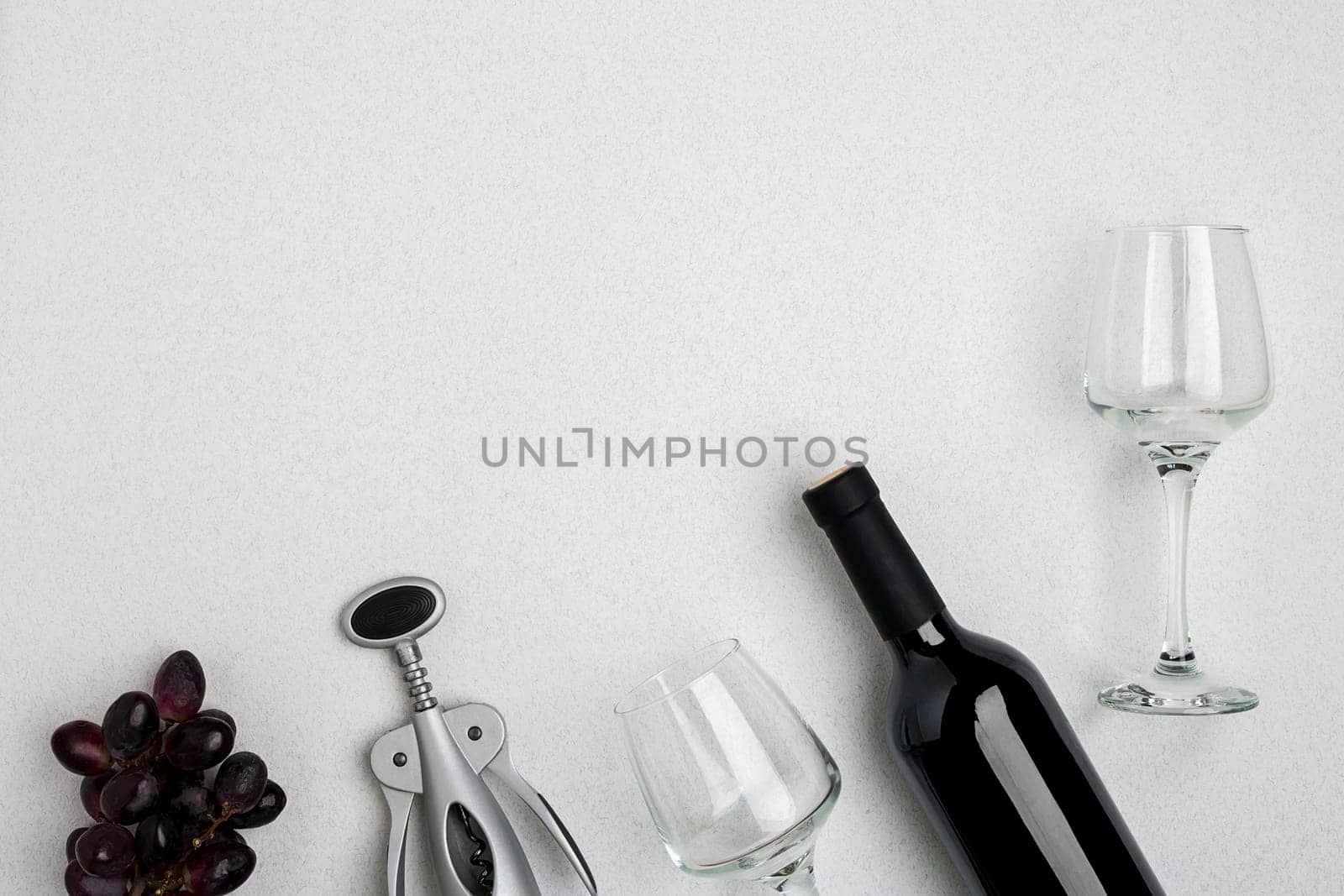 Red wine bottle, glasses and corkscrew over white background. Top view with copy space. Flat lay