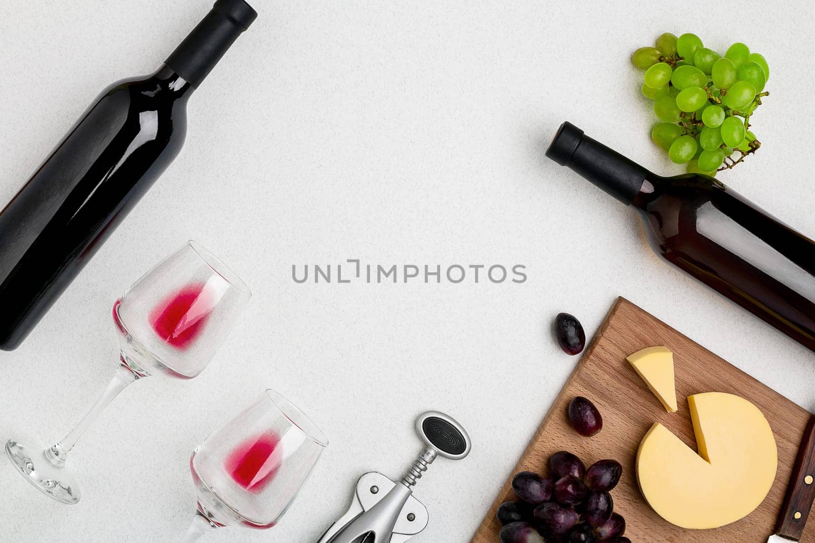 Two wine glasses with red wine,bottle of red wine and cheese on white background.Horizontal view from the top. Mock-up. Copy space. Flat lay