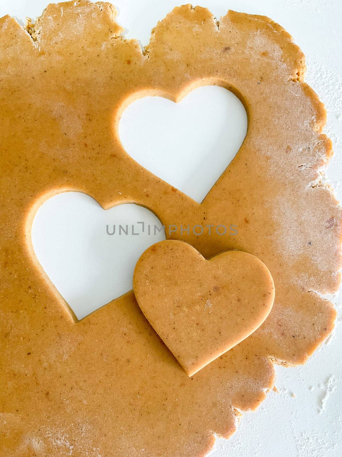 The process of making heart cookies. Top view of raw dough, rolling pin for baking