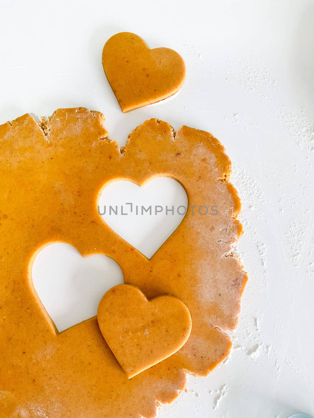 The process of making heart cookies. Top view of raw dough, rolling pin for baking