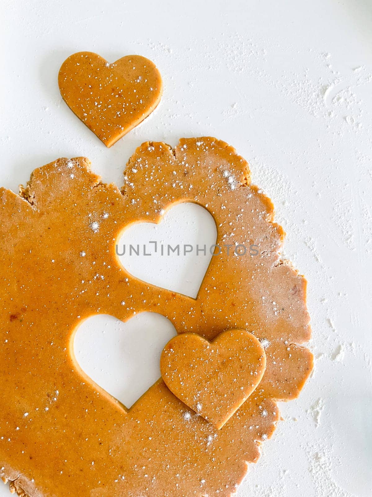 The process of cooking heart cookies. Top view of raw dough, rolling pin and baking cutter