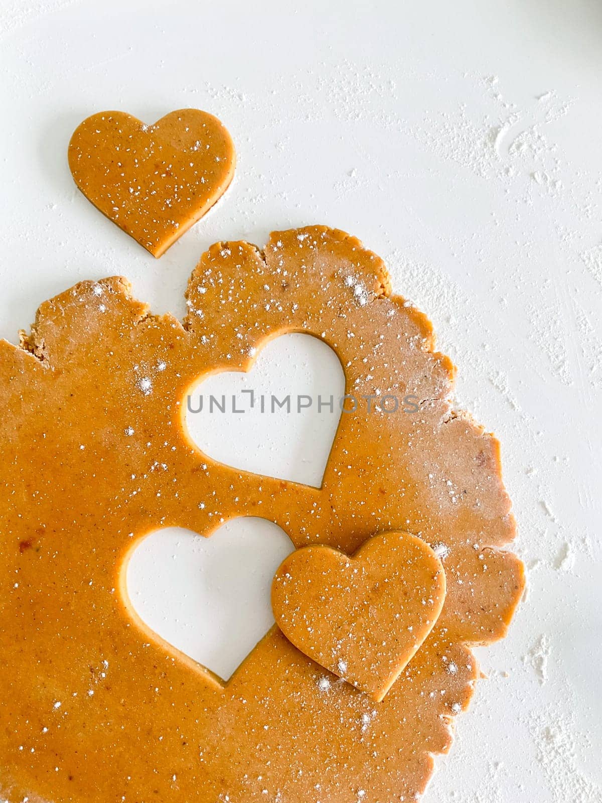 The process of cooking heart cookies. Top view of raw dough, rolling pin and baking cutter