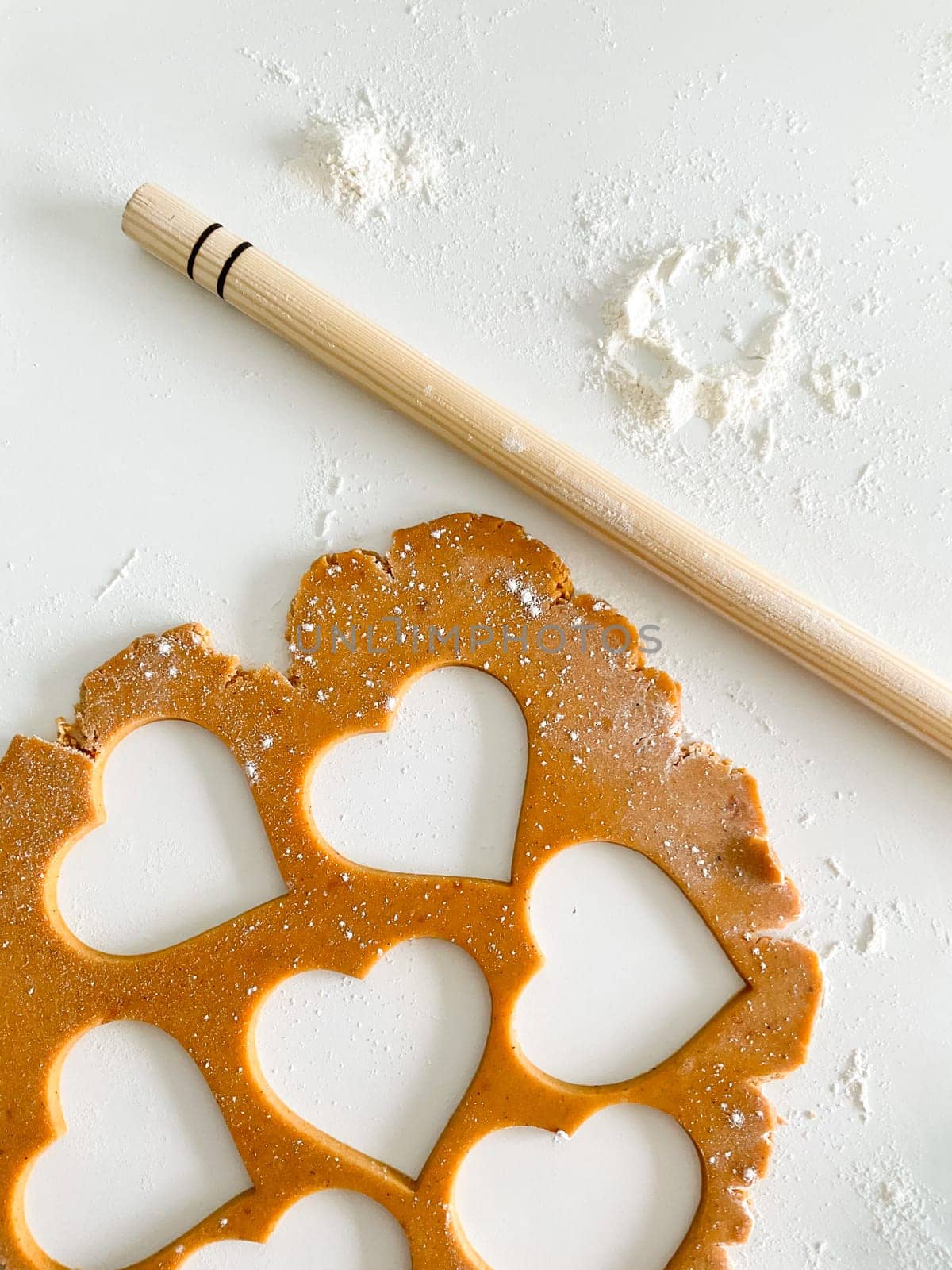 The process of cooking heart cookies. Top view of raw dough, rolling pin and baking cutter