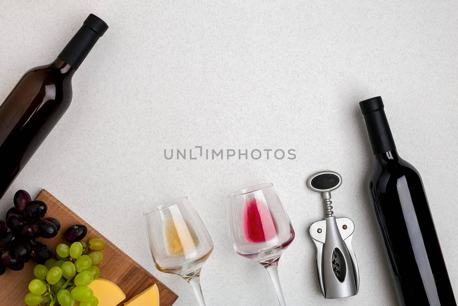 Glasses and bottles of red and white wine on white background from top view. Copy space