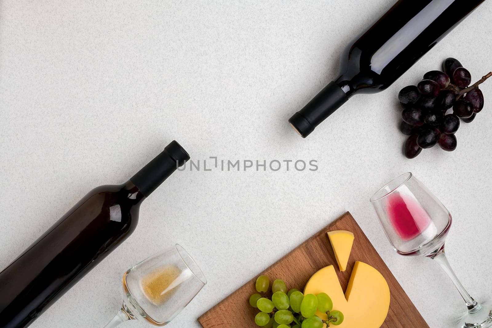 Two glasses of white and red wine, cheese and grapes. Two bottles of wine. Top view with copy space