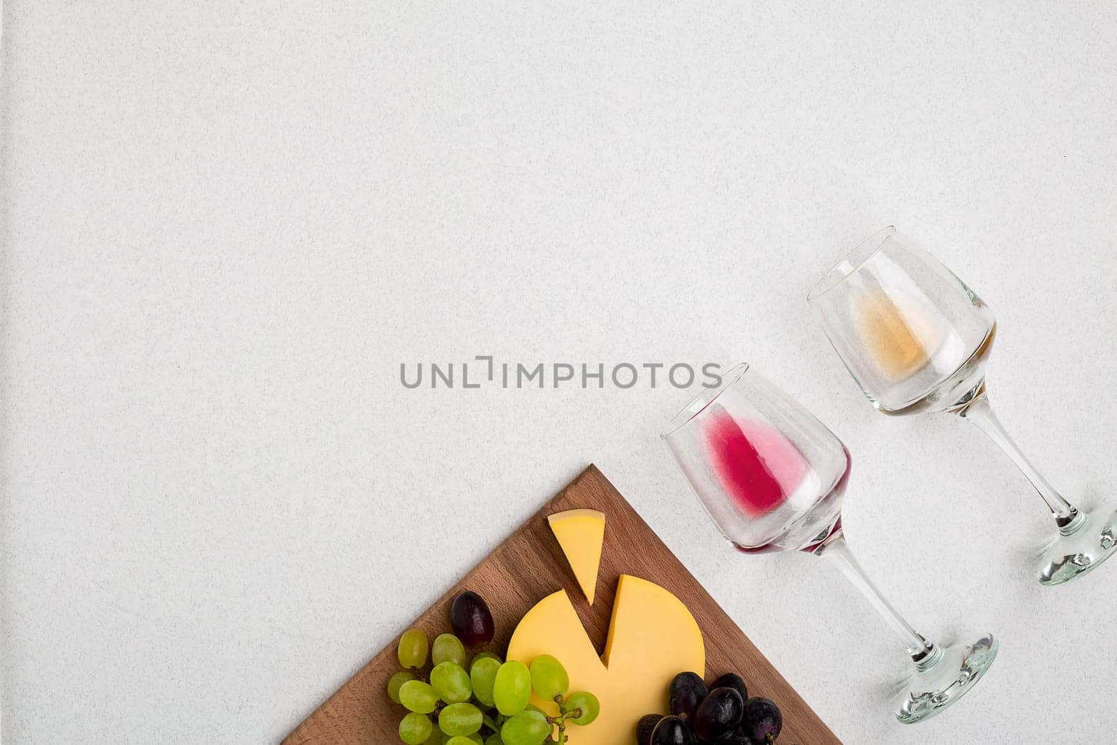 Two glasses of white and red wine, cheese and grapes. Top view with copy space