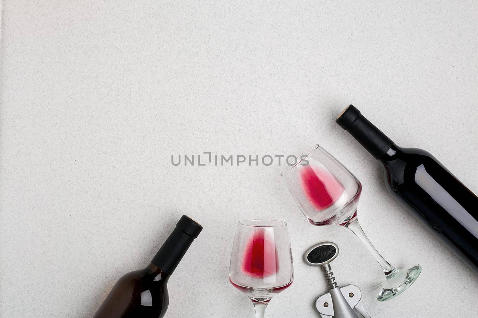 Glasses and bottles of red and white wine on white background from top view. Copy space