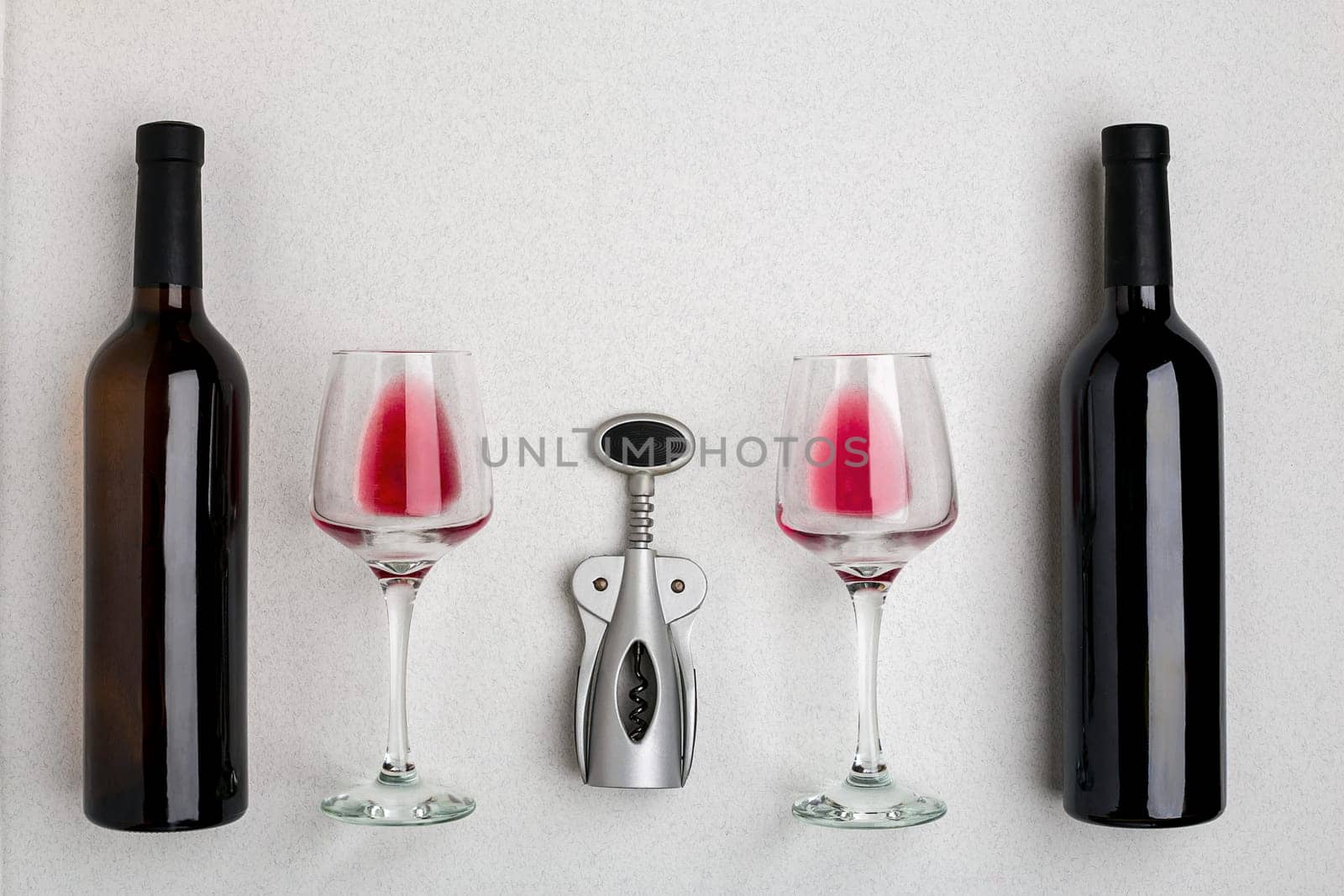 Glasses and bottles of red and white wine on white background from top view. Copy space
