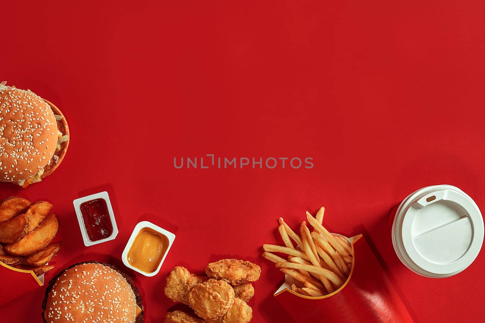 Burger and Chips. Hamburger and french fries in red paper box. Fast food on red background. Hamburger with tomato sauce. Top view, flat lay with copyspace
