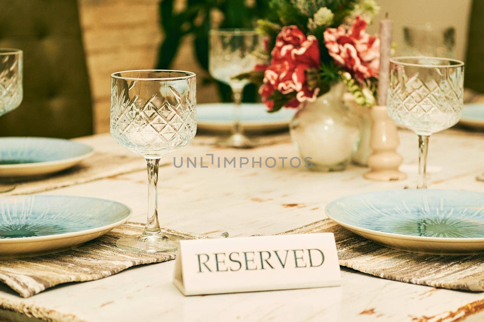 the main meal of the day, taken either around midday or in the evening. Reserved table in a cafe restaurant with wine glasses and plates.