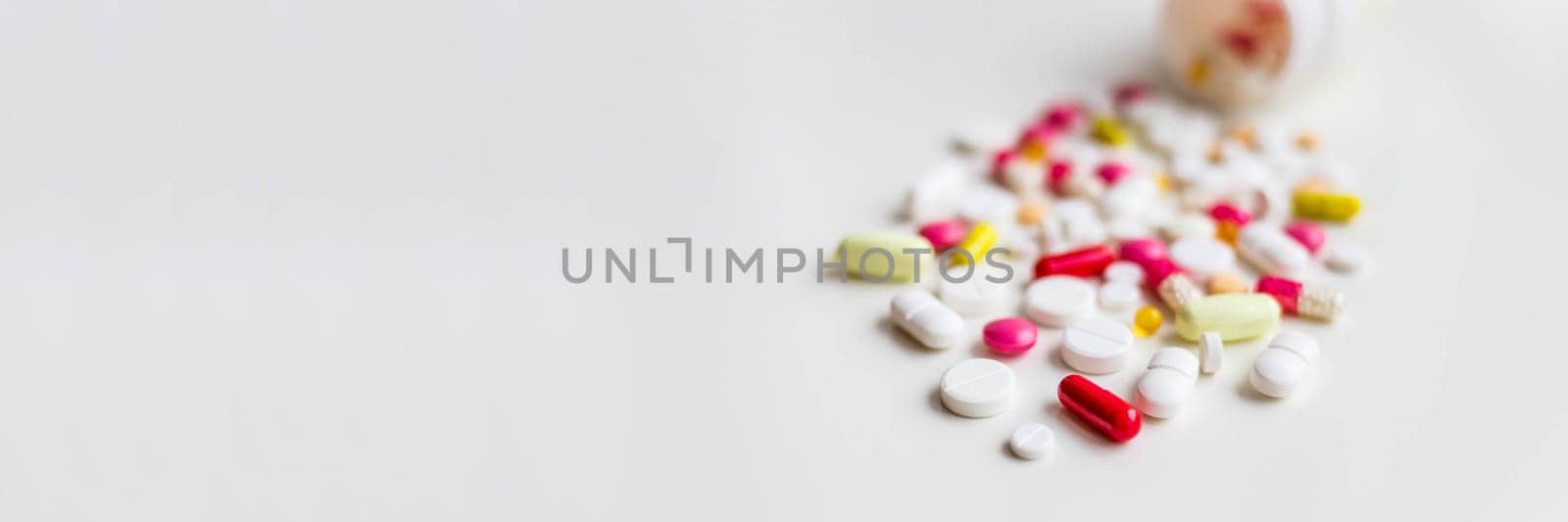 Pile of colorful medicine pills, white, blue, yellow and red, sitting on white background