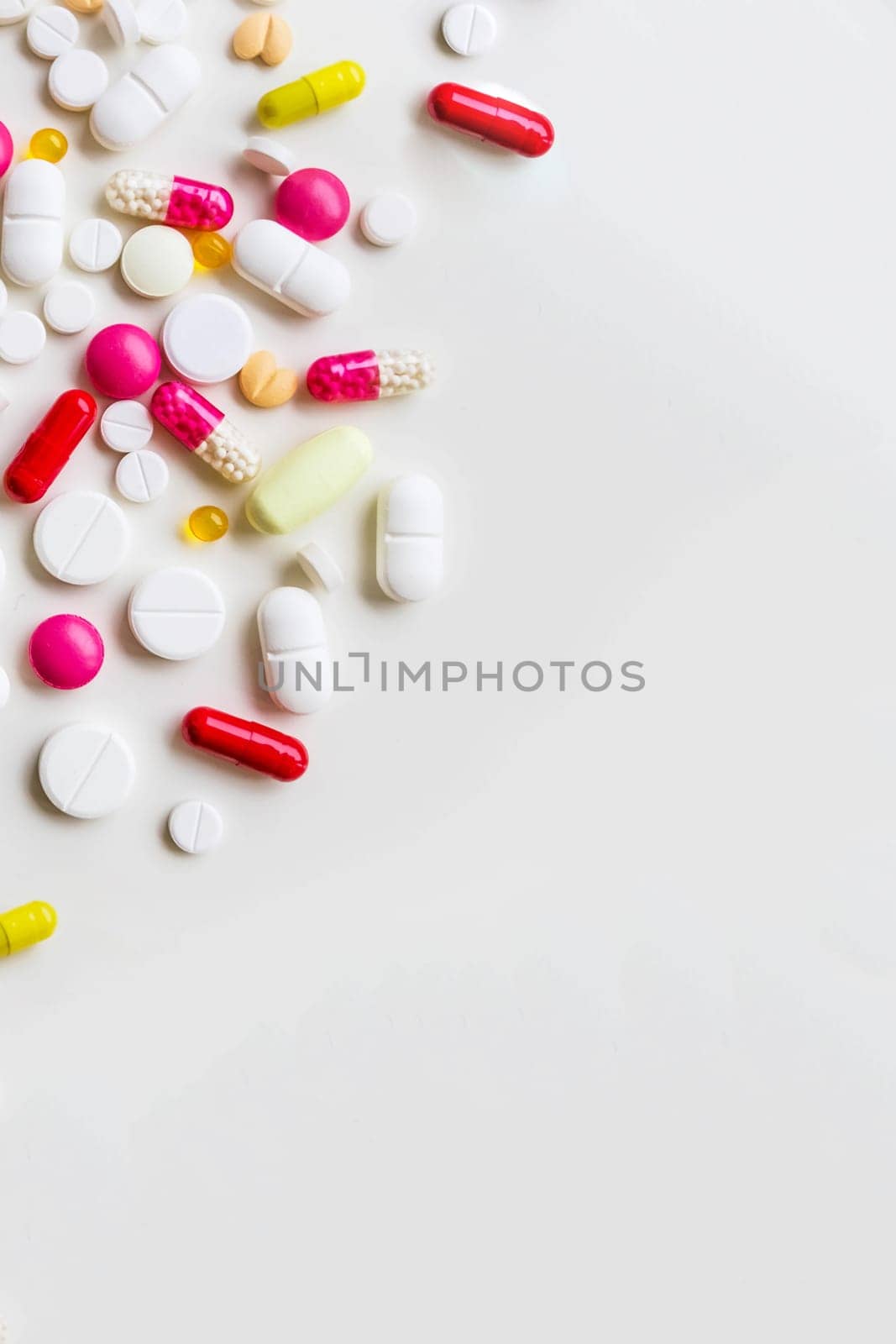 Pile of colorful medicine pills, white, blue, yellow and red, sitting on white background