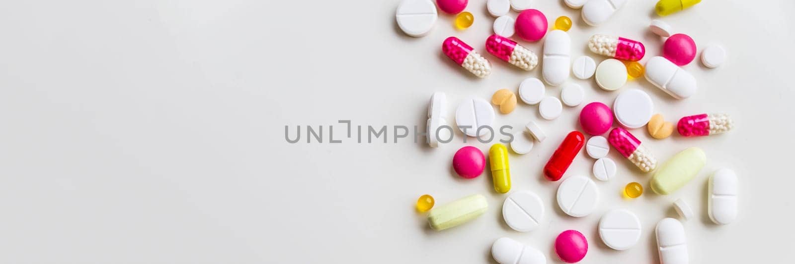 Pile of colorful medicine pills, white, blue, yellow and red, sitting on white background