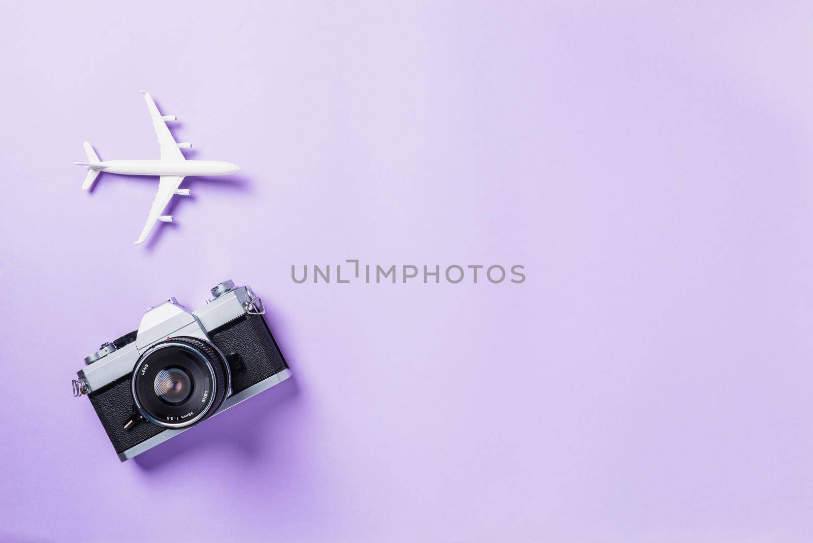Top view flat lay mockup of retro camera films, airplane traveler accessories isolated on a purple background with copy space, Business trip, and vacation summer travel concept