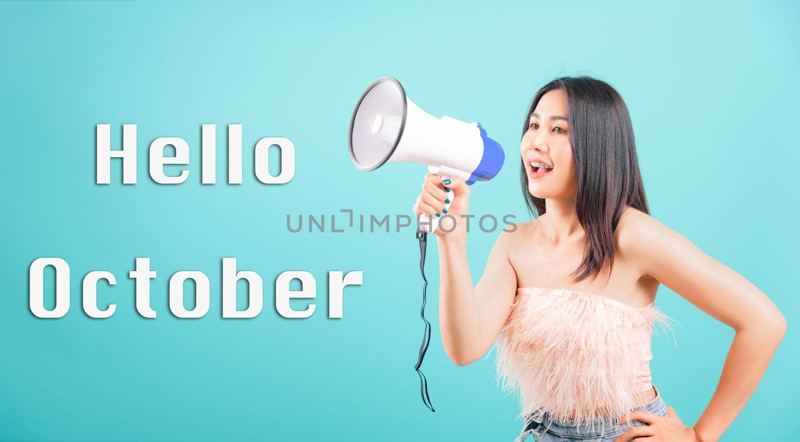 Hello October, Smiling face portrait Asian beautiful young woman her using megaphone to say hello studio shot isolated on blue background