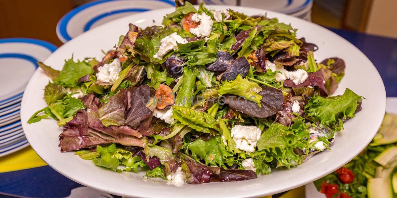 Green salad with fig and goat cheese, served on white plate