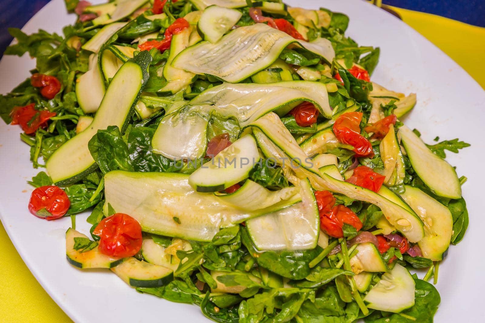 Green salad with cucumber and cherry tomato, served on white plate