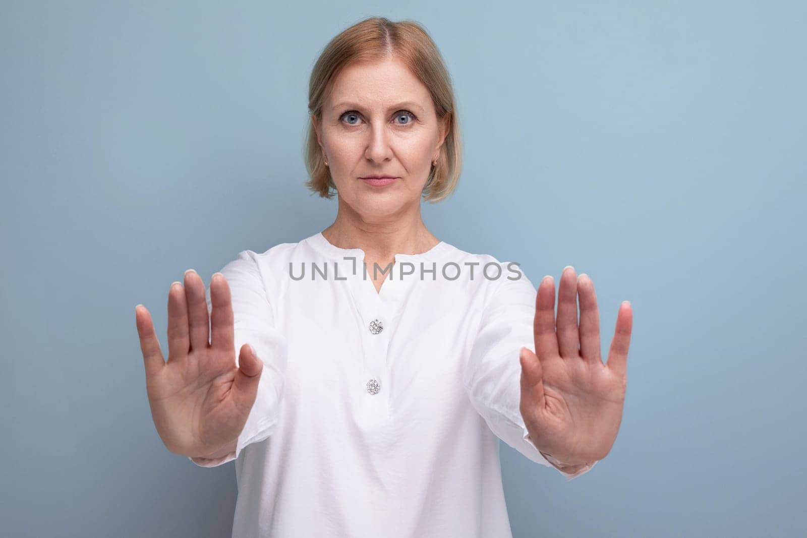 serious blond bob middle aged woman in white blouse in menopause refuses on studio background.