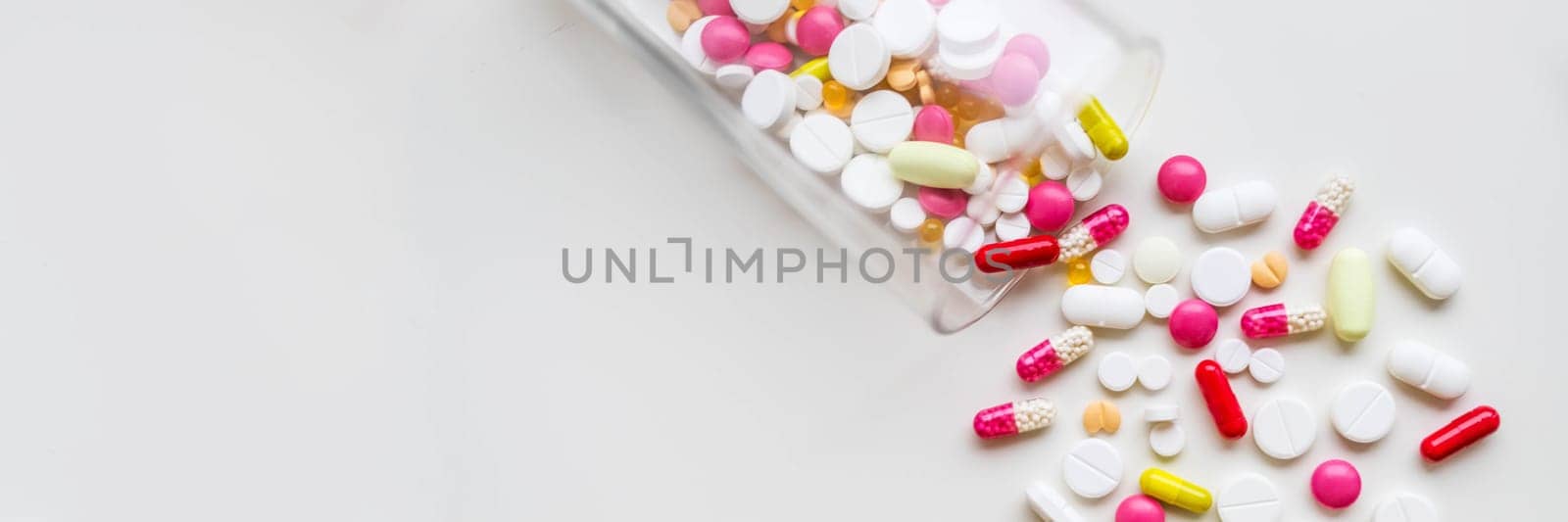 Many white tablets spilling out of package, Close up pills spilling out of pill bottle on blue background.