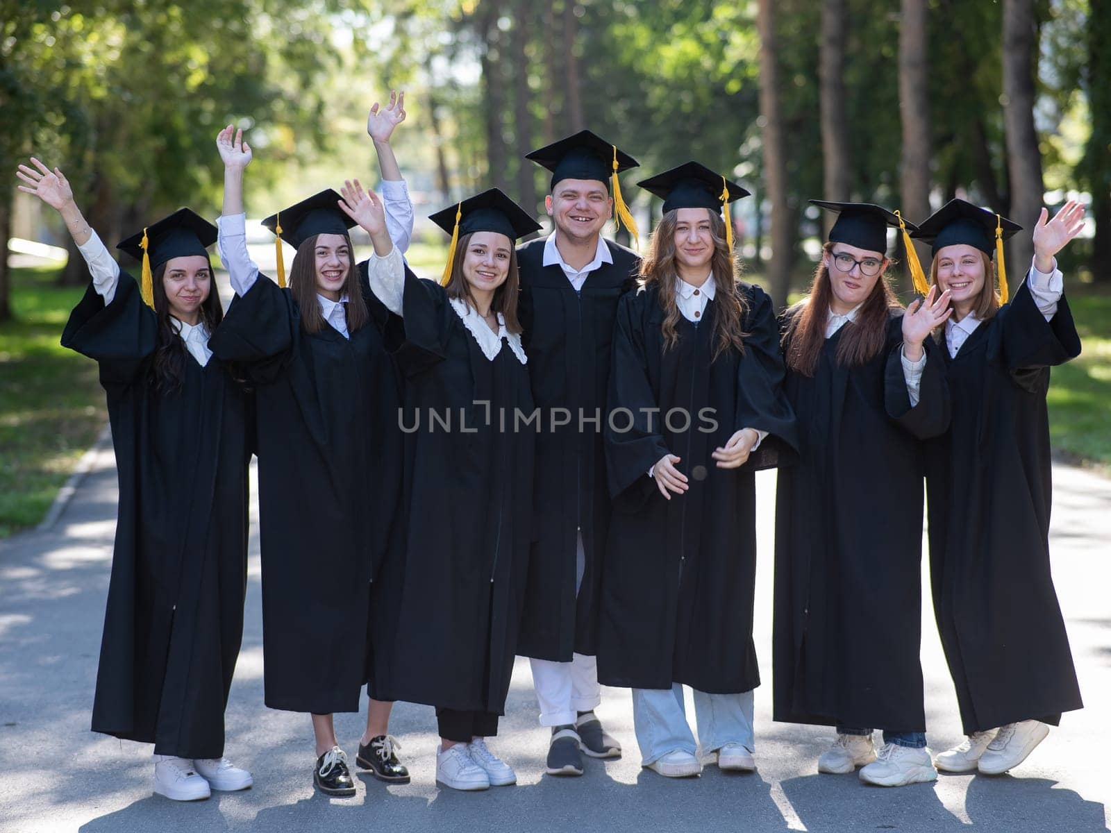 Group of happy graduates in robes outdoors