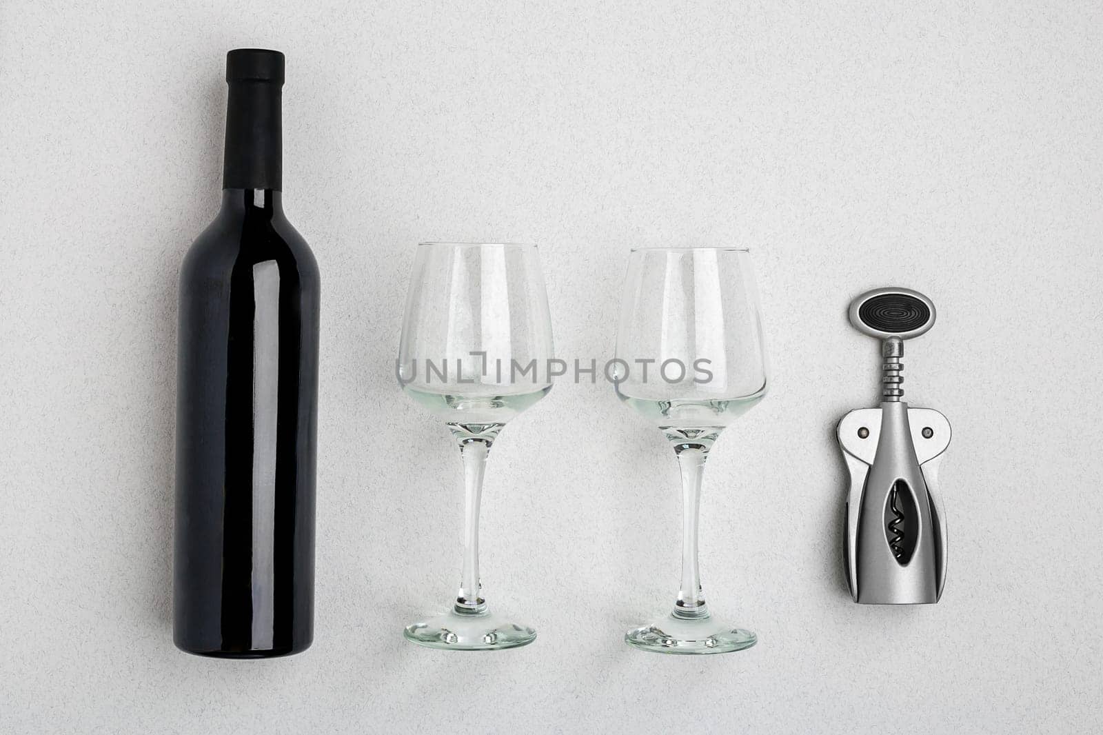Red wine bottle, glasses and corkscrew over white background. Top view with copy space. Flat lay