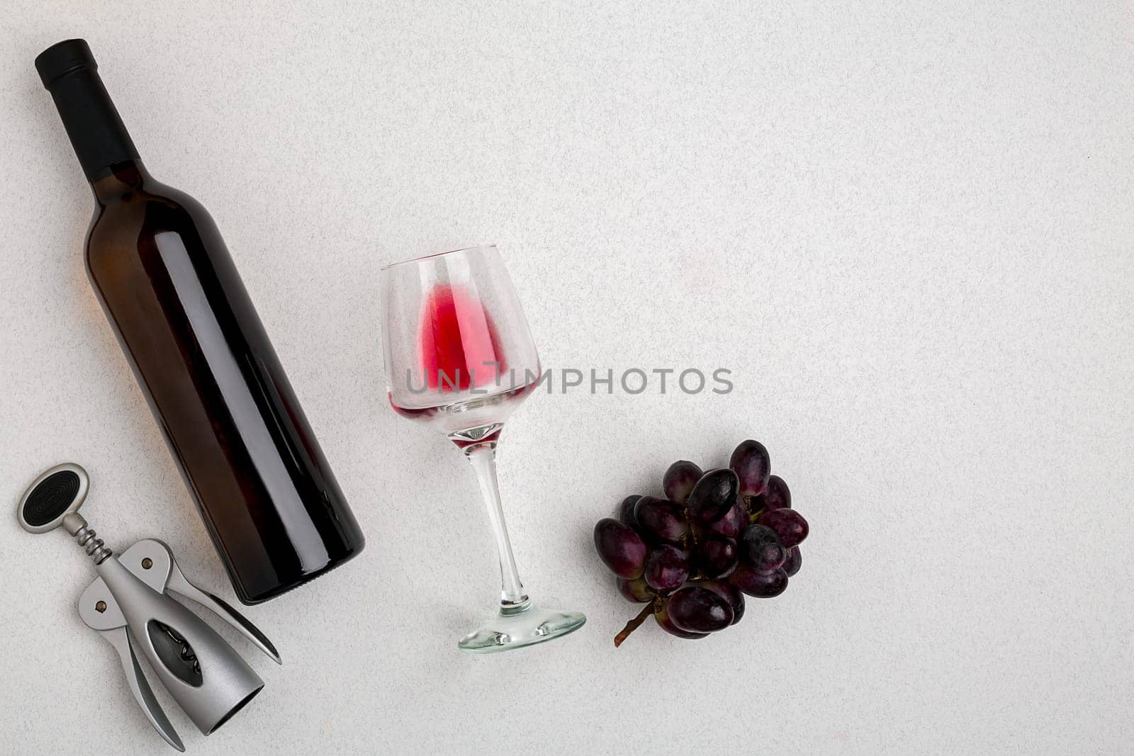 Overhead angled view of a large bottle of red wine, drinking glass on white background by nazarovsergey