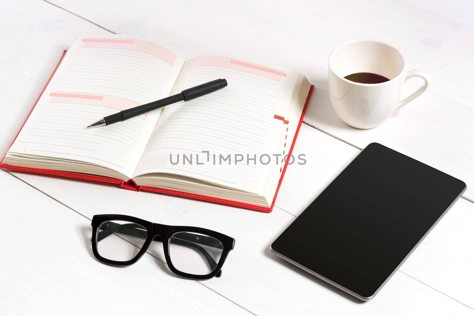 Office table desk with set of supplies, white blank notepad, cup, pen, tablet, glasses on white background. Top view by nazarovsergey