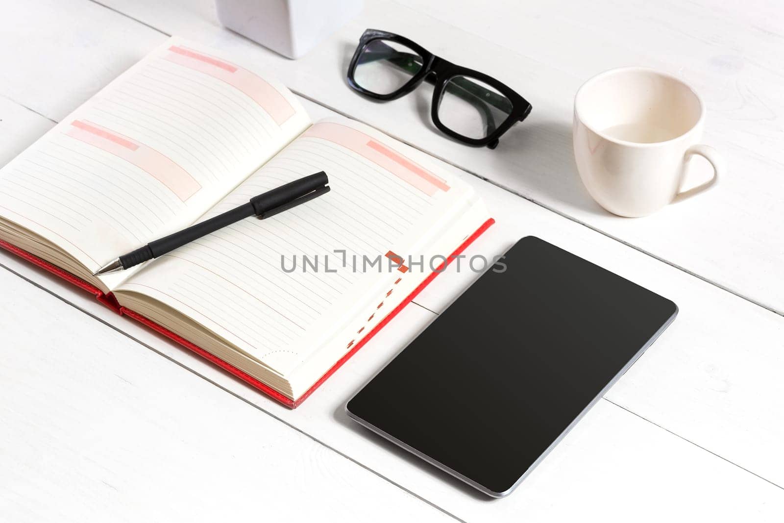 Stylish minimalistic workplace with tablet and notebook and glasses in flat lay style. White background. Top view. Copy space