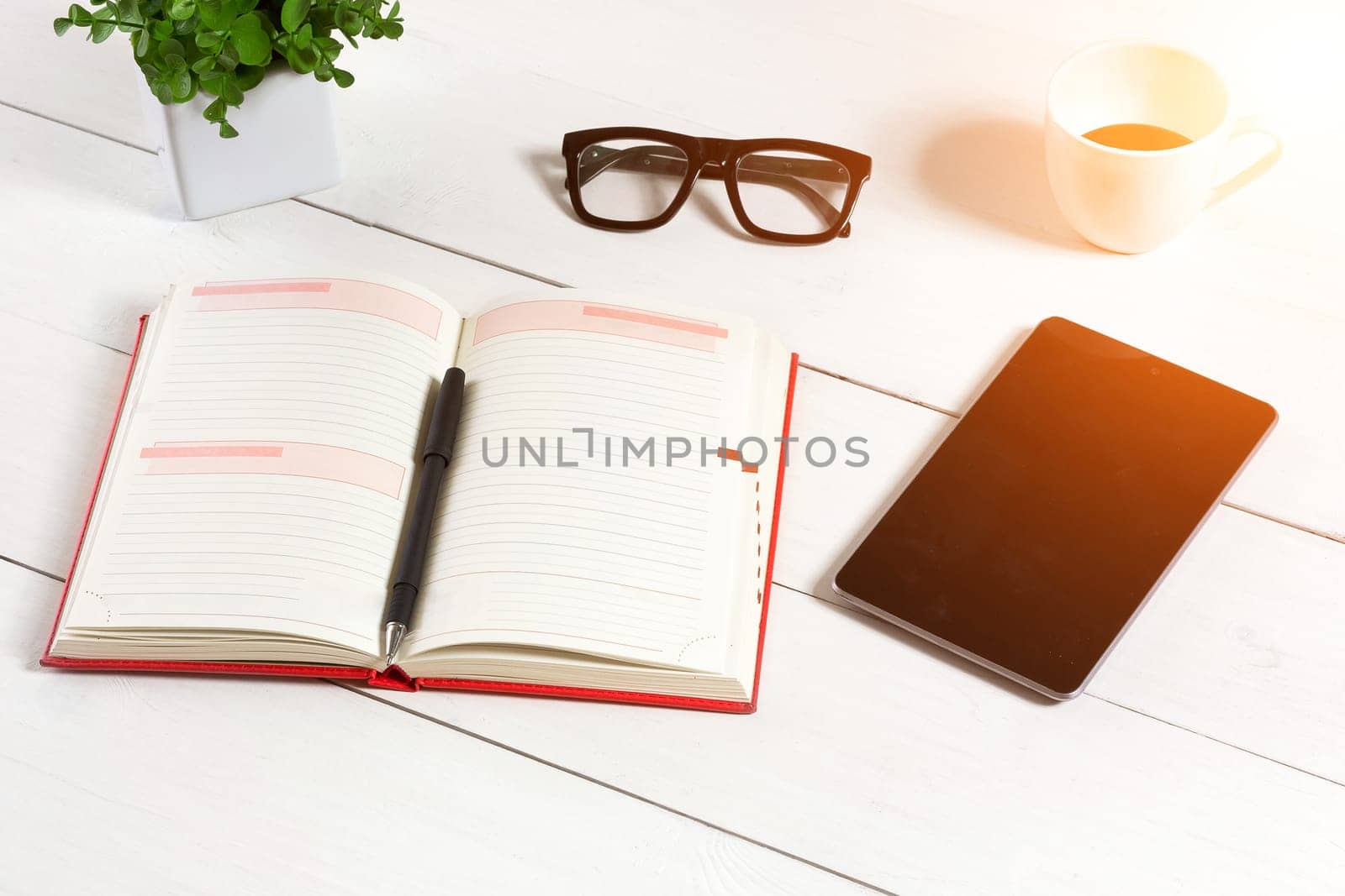 Office table desk with set of supplies, white blank notepad, cup, pen, tablet, glasses, flower on white background. Top view by nazarovsergey