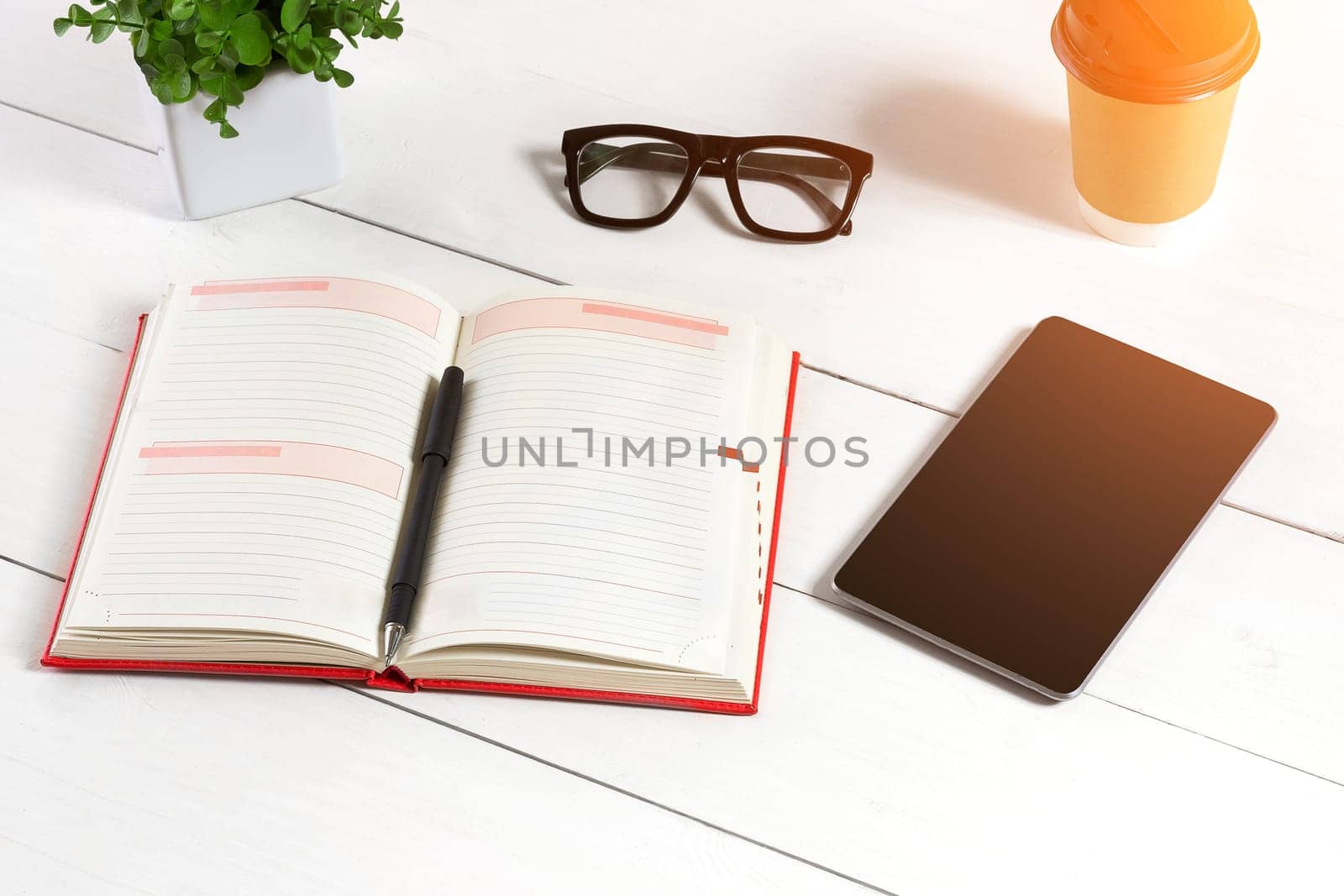 Stylish minimalistic workplace with tablet and notebook and glasses in flat lay style. White background. Top view. Copy space. sun flare