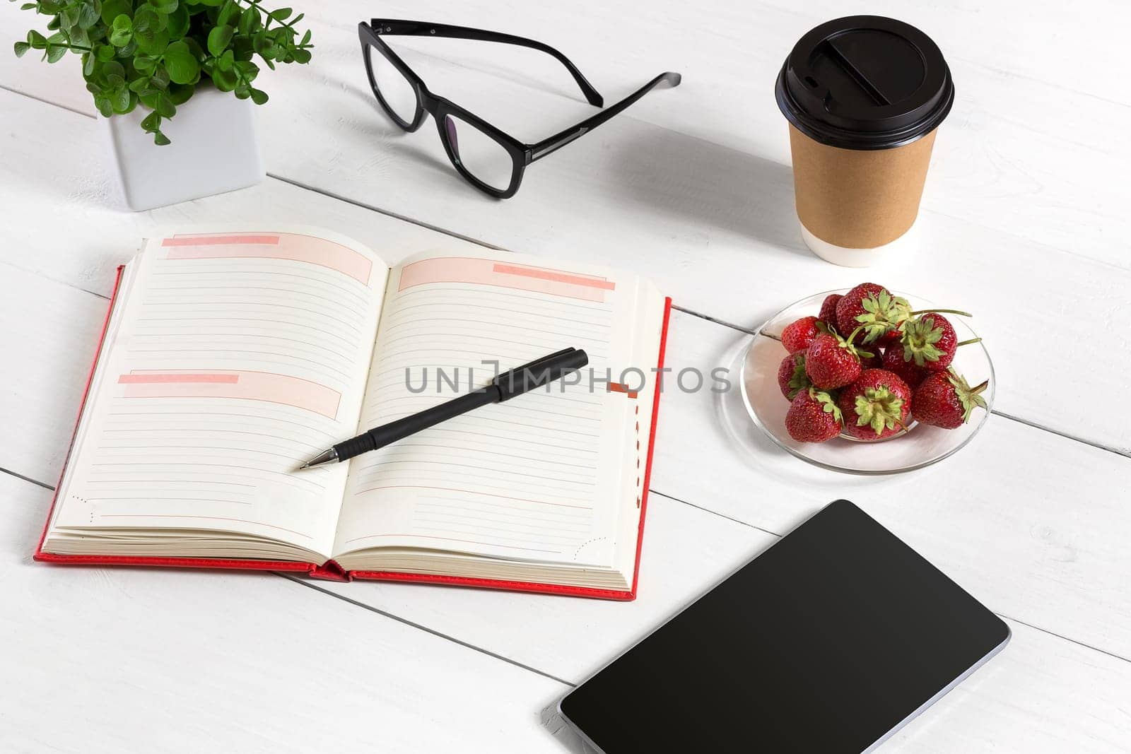 Office table desk with set of supplies, white blank notepad, cup, pen, tablet, glasses, flower on white background. Top view by nazarovsergey