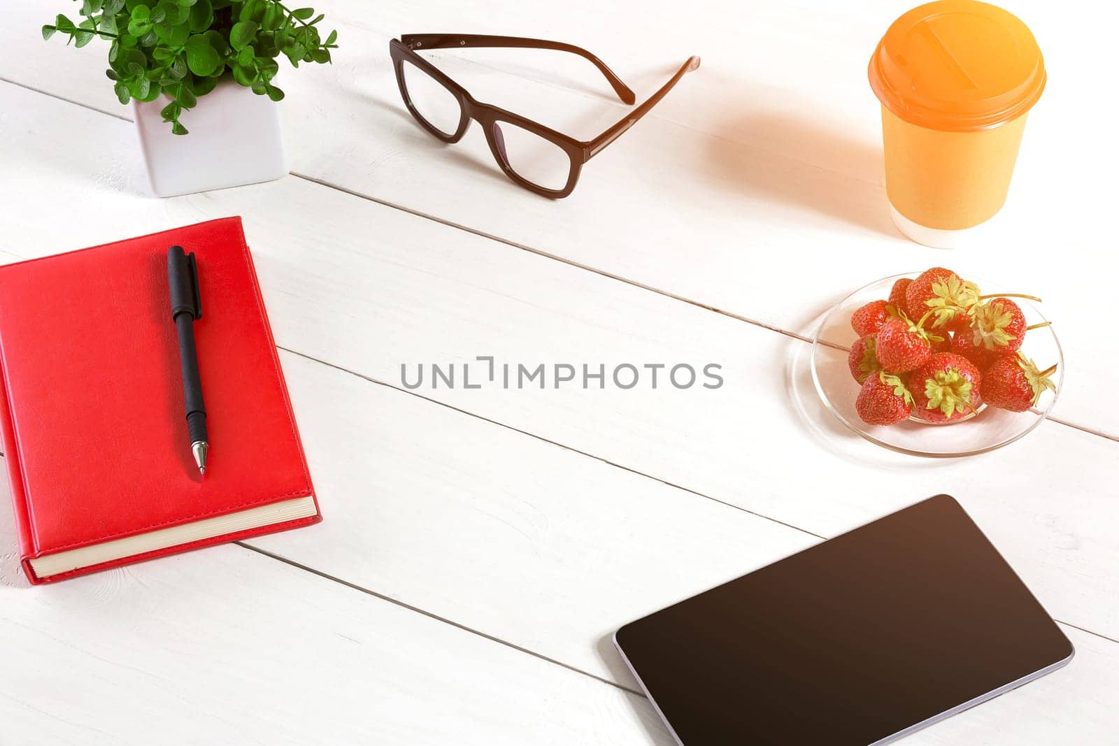 Office table desk with set of supplies, red notepad, cup, pen, tablet, glasses, flower on white background. Top view by nazarovsergey