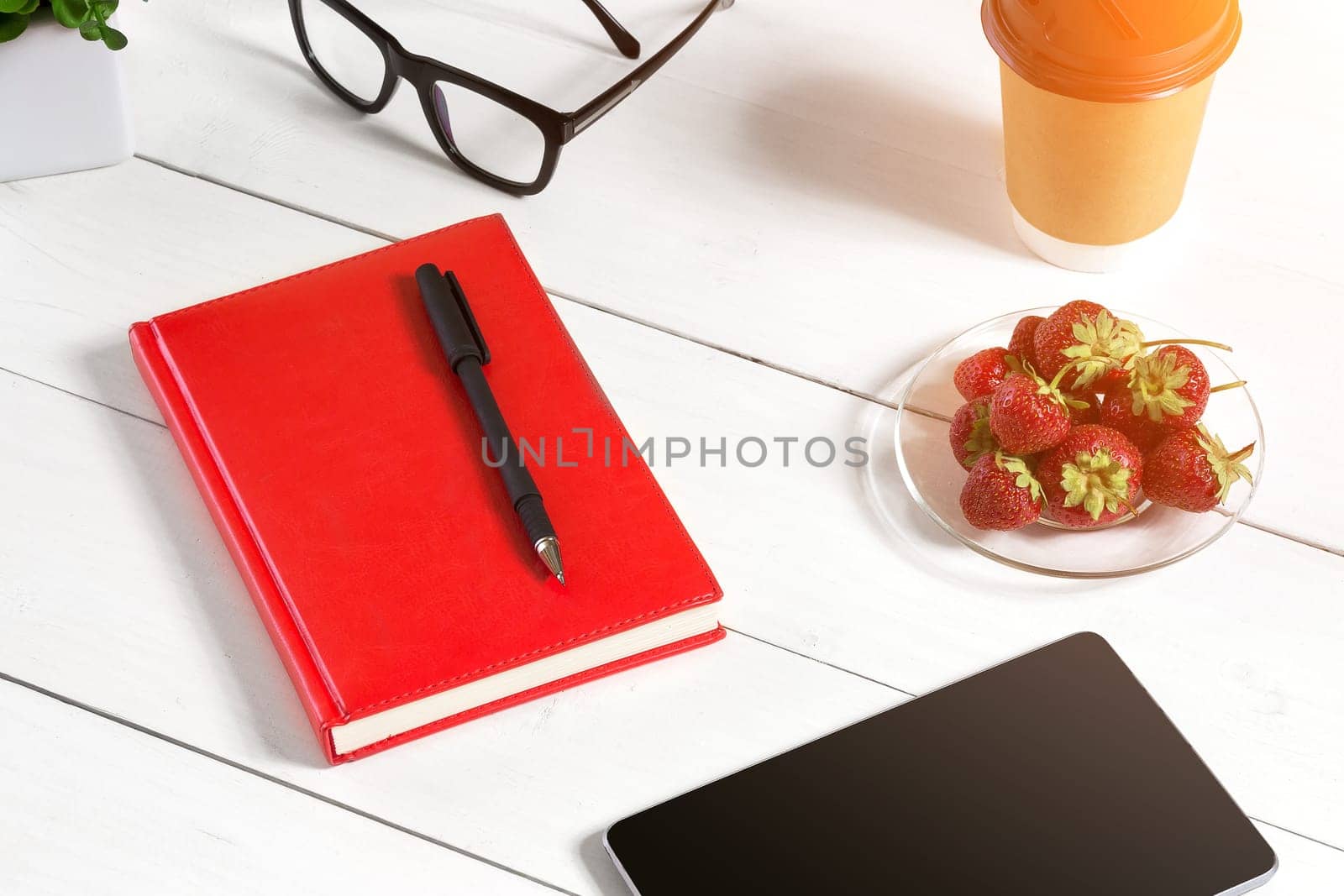 Stylish minimalistic workplace with tablet and notebook and glasses in flat lay style. White background. Top view. Copy space. sun flare