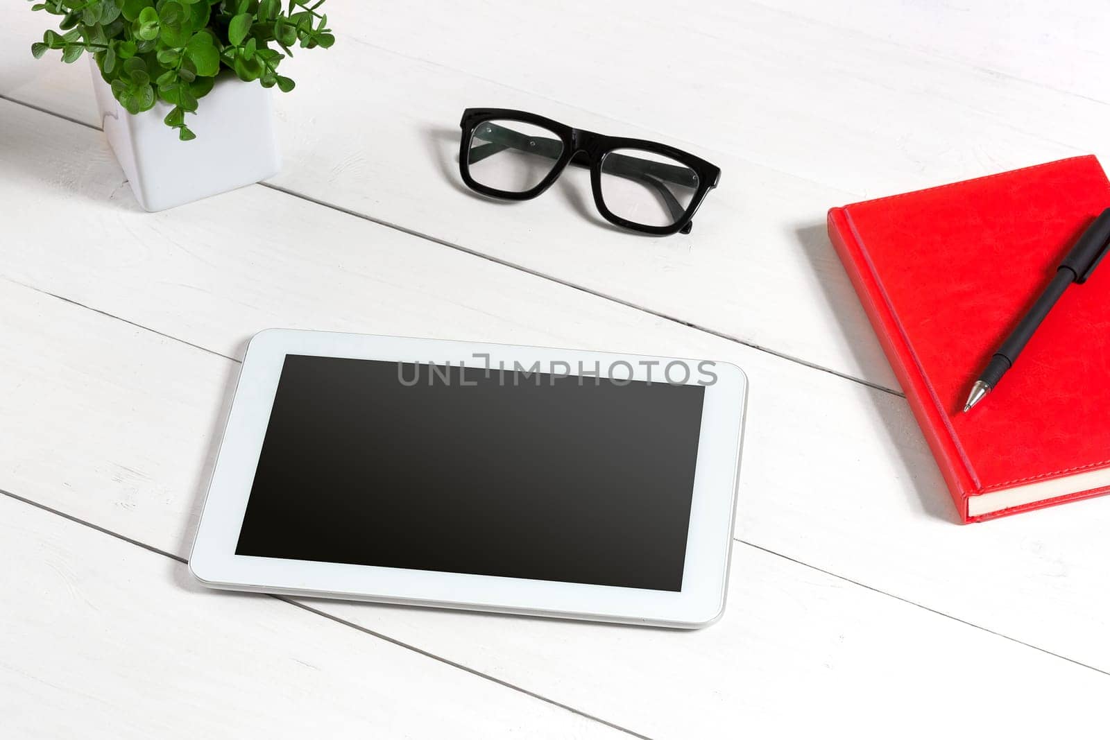 Stylish minimalistic workplace with tablet and notebook and glasses in flat lay style. White background. Top view. Copy space